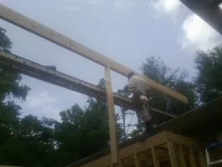 Carpenter setting a ridge beam over a new addition frame — Ice Dam Removal by Roofing Brothers in Malabar