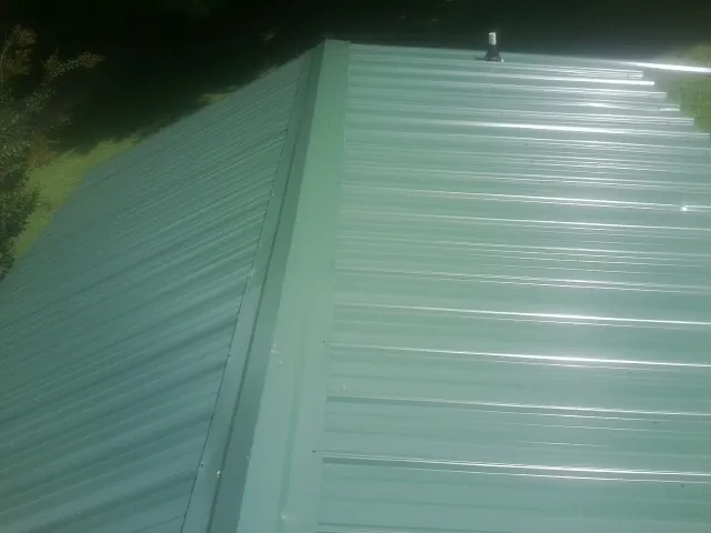 New green metal panels meeting at the ridge of a roof — Flat Roof Repair work by our crew in Malabar