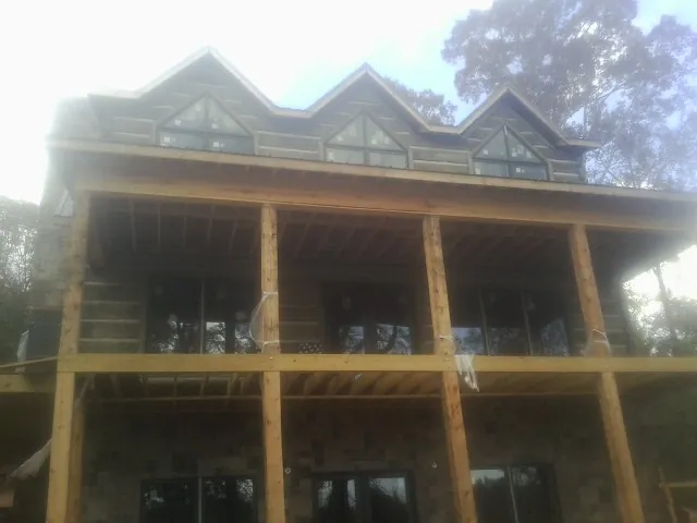Dormers and porch framing on a large log home under construction — Roof Coating work by our crew in Malabar