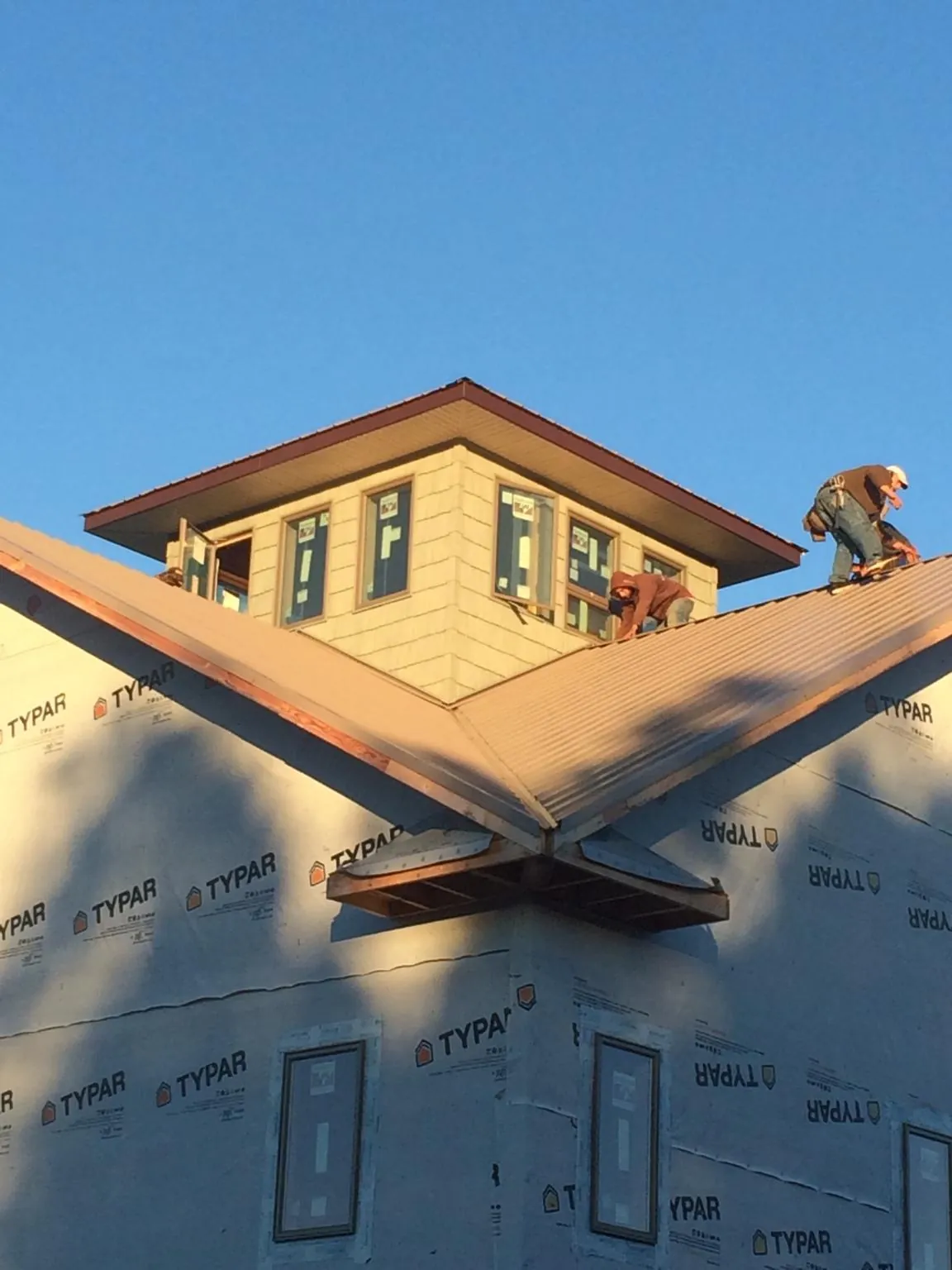Roofers working around a rooftop cupola on a new metal roof at sunset — Roof Waterproofing in Malabar by Roofing Brothers